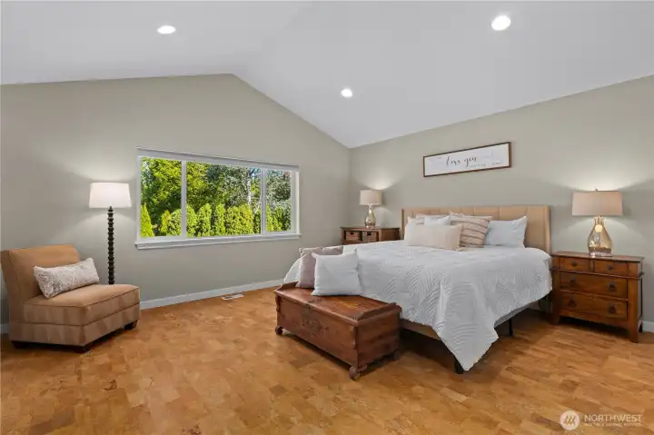 The primary suite boasts vaulted ceilings and a private view to the backyard.