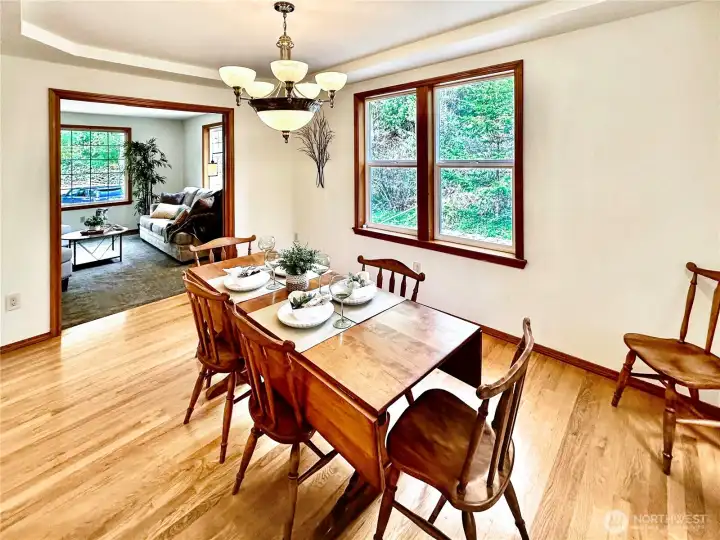 Formal dining room with rich wood floor, tray ceiling and easy access to both the living room and kitchen.