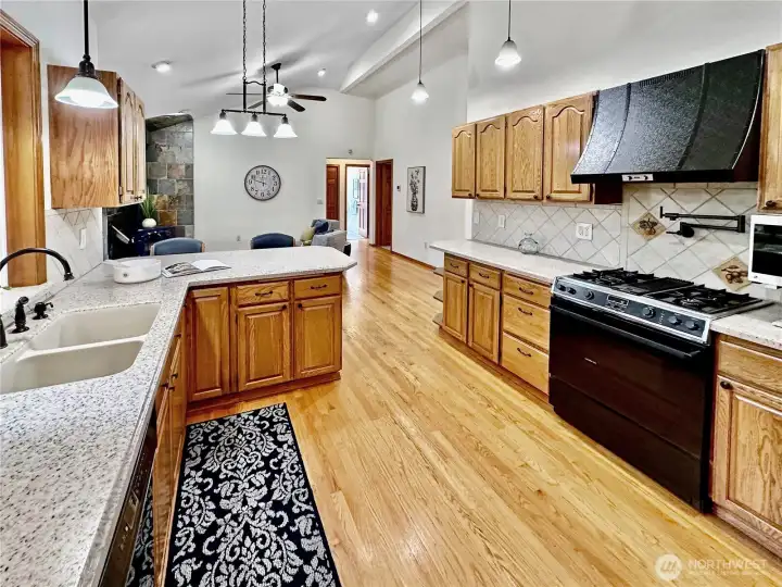 Kitchen features include Corian counters, eating bar, oak floors, gas cook top range with pot filler faucet and full tile backsplash.
