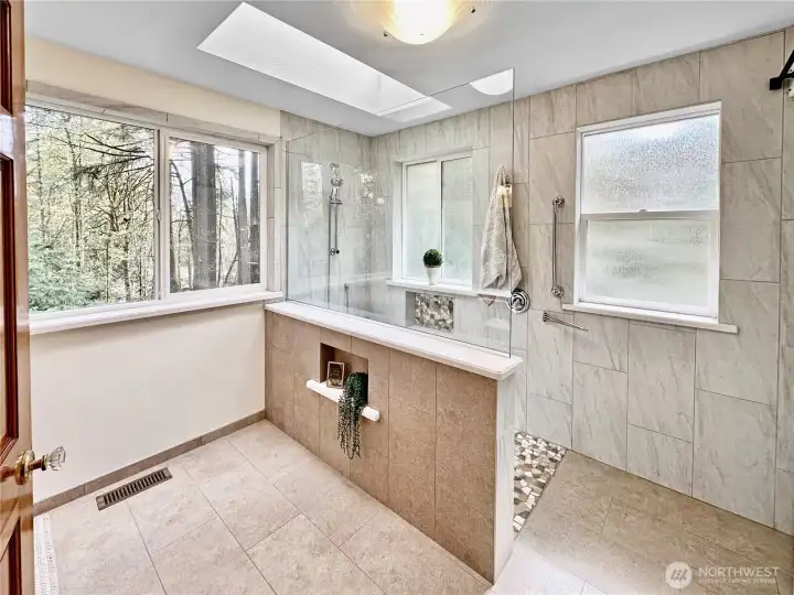 Elegant primary bath with tile floor, skylight and lovely walk-in shower.