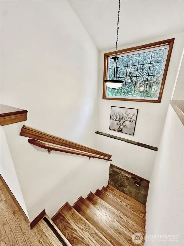 The stair well to the lower level with wood stairs and slate landing is located just off the entry hall.
