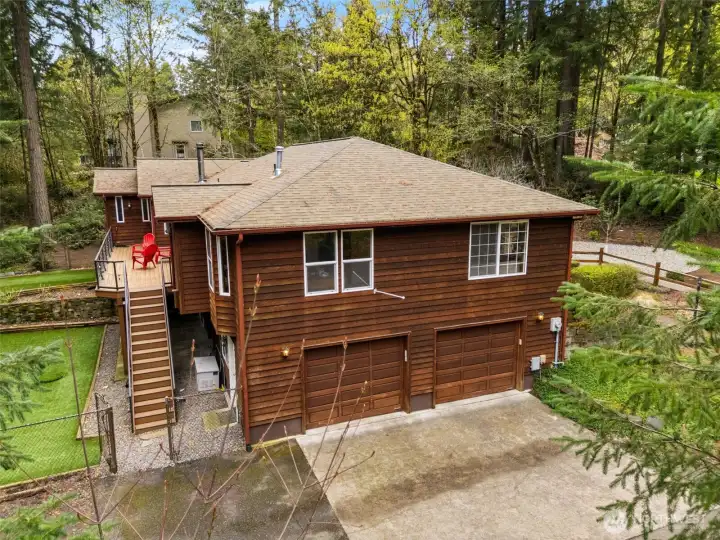 Side View showing the 2 car garage, off street parking and access to both the upper deck and lower level patio with access to the rec room.