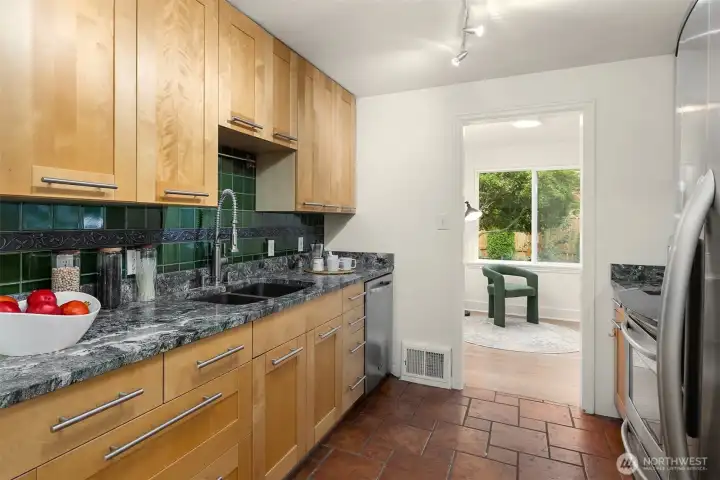 Updated kitchen features stainless appliances, slab granite counters and a tile backsplash