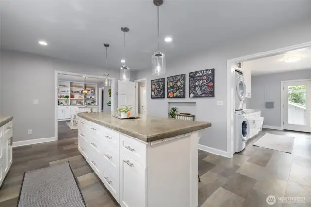 Another view of the kitchen, looking into the living and dining room at left, and to the laundry and mudroom at right.  Notice the built-in power and UBC charging ports on the end of the island.