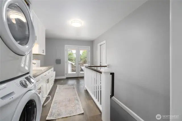 Laundry and mudroom, with French doors leading to the covered deck and fenced back yard.  Door on wall at right leads to the garage, and stairs lead down to the finished basement.