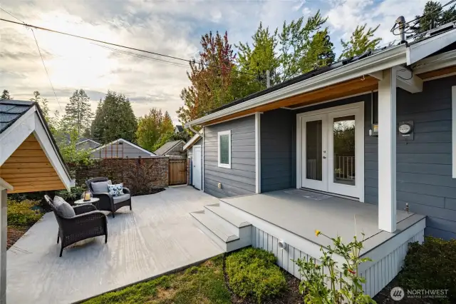 Back patio.  Gate leads to the alley.  Solid white door by the gate leads to a huge storage shed off the garage.