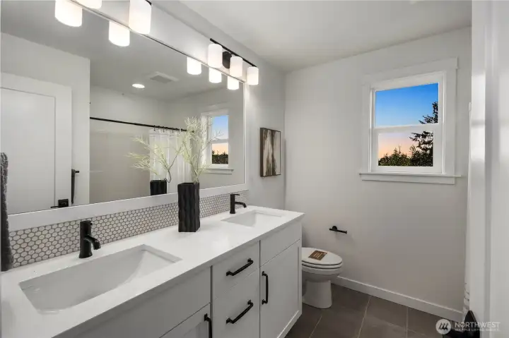 Upper Hall Bath: Full bath features a dual vanity with quartz counters, modern fixtures, and stylish tile details. Perfectly situated to serve the secondary bedrooms with convenience and comfort.    Photos are from the model home at Foxmoore and for visualization purposes only. Plans, colors, building orientation, finishes, home outlook, and other details can and WILL vary.