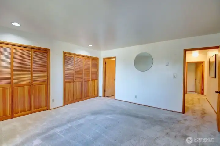 View of primary bedroom looking towards hallway and door to bathroom.