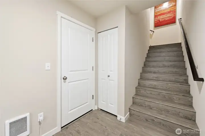 Stairs up to main level and door to large tandem garage, storage and patio.
