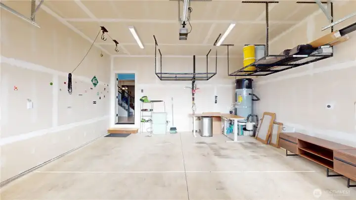 Two car garage with electric opener, bike lift, overhead storage, and 240volt EV plug. Image 1 of 2.