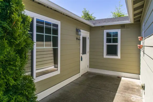 Back main entrance tucked behind the garage. Wide and level paved path from the driveway with a no step threshold.