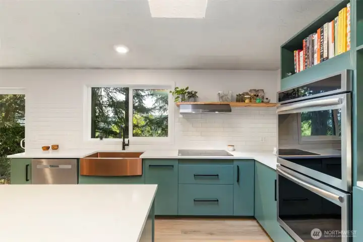 A cook's dream with custom cabinets, tile backsplash, quartz countertops, farmhouse sink, double oven, drawers in the island and new windows bringing in light and to enjoy the view.