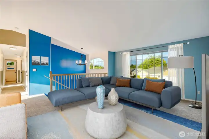 Step inside to a vaulted living room flooded with natural light, highlighting the airy, open-concept layout.  [Photo is virtually staged]