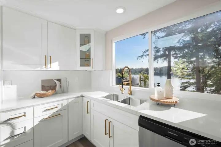 Stylish sink and brushed gold faucet framed by sweeping water views