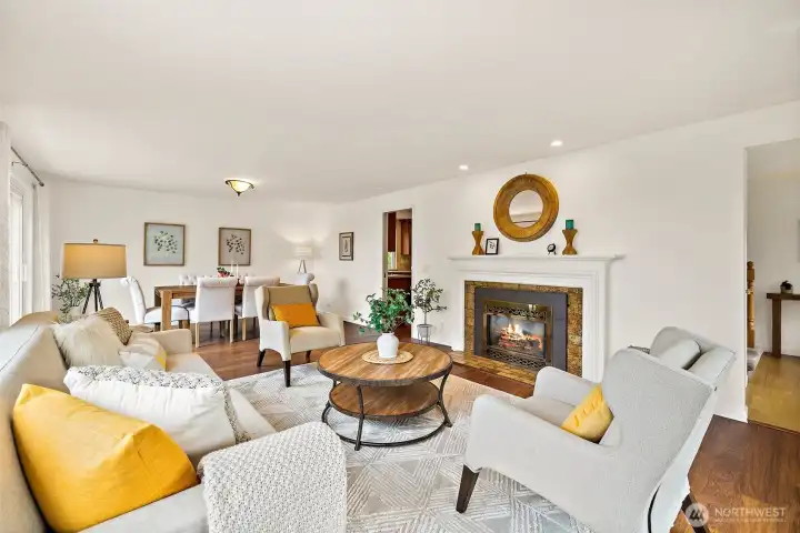 Inviting living room with gas fireplace adjoining formal dining room with walls of windows.