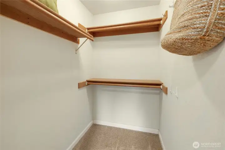 Large walk-in closet sits between primary bedroom and bathroom, with small sitting area