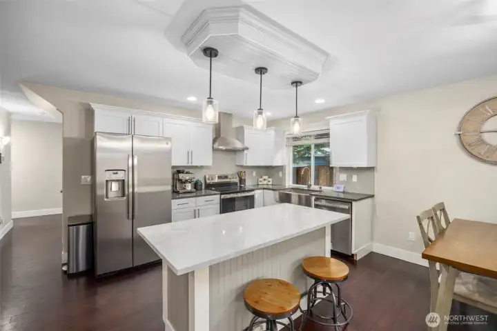 Spacious kitchen with a large farmhouse sink, expansive island, quartz countertops, tile backsplash, gorgeous cabinetry, & stainless steel appliances.