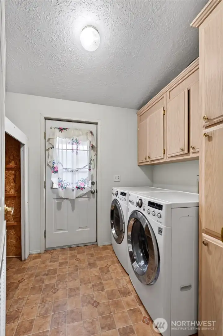 Laundry room with cabinets, storage closet, furnace and back door.  Washer and dryer included in sale.