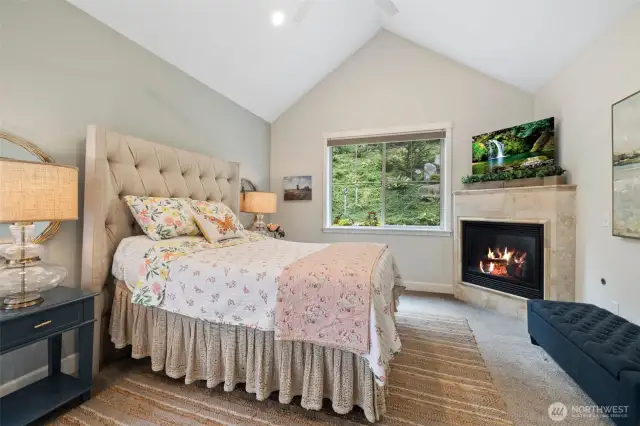 Onto the primary suite...cathedral ceilings, gas fireplace and a beautiful view outside.