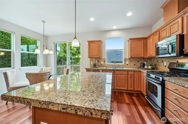 Large island topped with granite and a gas stove.
