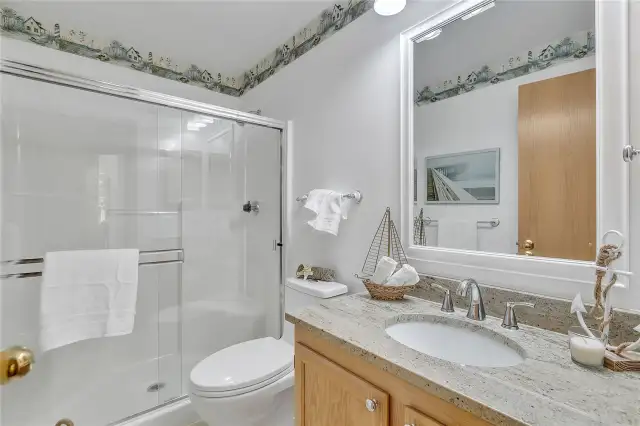 The updated main-floor bath features a sleek granite countertop, stylish tile flooring, and a new toilet, LED light and fan.
