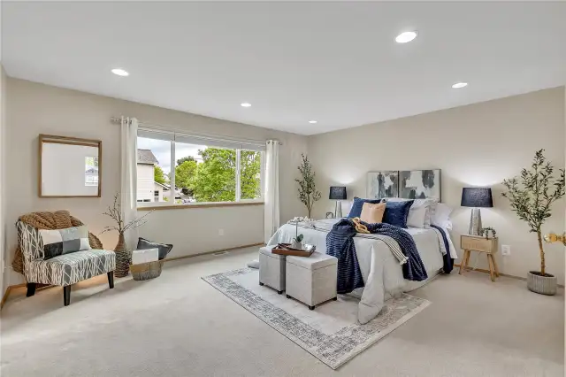 The spacious primary suite offers a serene retreat, beautifully illuminated by canned lighting, creating a warm and inviting ambiance for relaxation