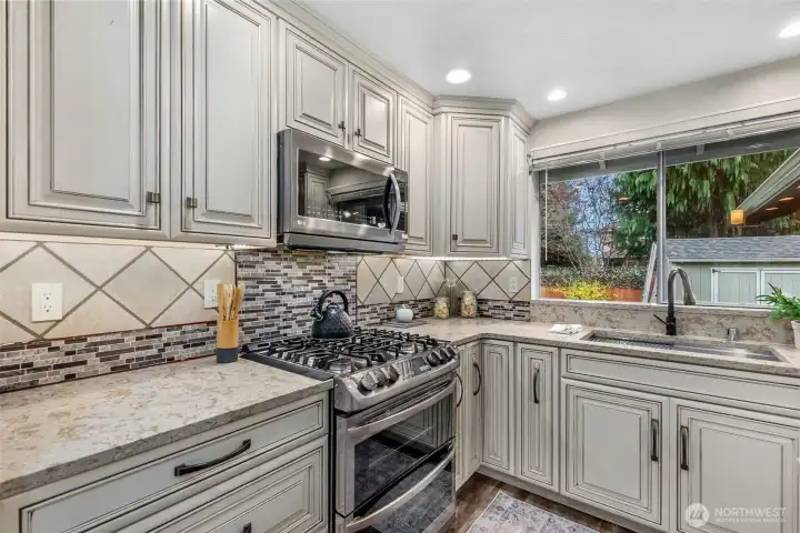 Gleaming quartz counterspace with coordinated tile backspash, large stainless sink & appliances...