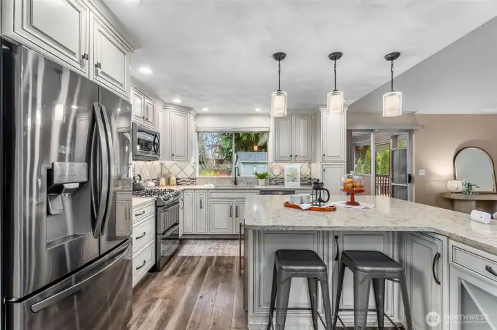 Stunning black stainless steel appliances include refrigerator, double oven with gas range, wine fridge, microwave & dishwasher.