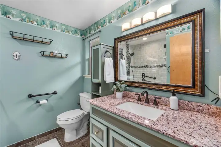 The primary bath with large walk-in shower, ceramic tile flooring & great storage options!