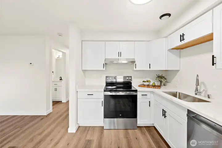 Gleaming Quartz Slab, Crisp White Cabinets, Stainless Appliances, Easy Care LVP Floor