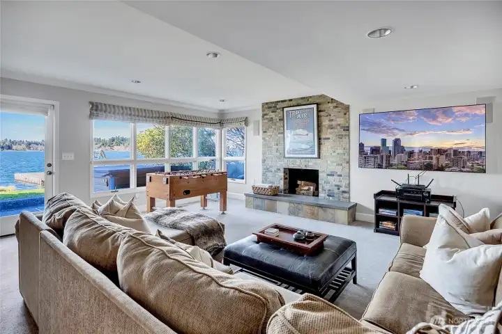 The lower level bonus room is designed for pure enjoyment, perfectly positioned just off the lake for easy access to the outdoors. A cozy fireplace anchors the space, creating the ideal setting for movie nights