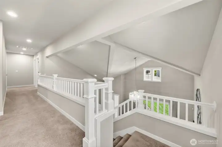 Vaulted ceilings and crisp white millwork greet you at the top of the stairs — an airy upper landing that sets the tone for the bedrooms beyond