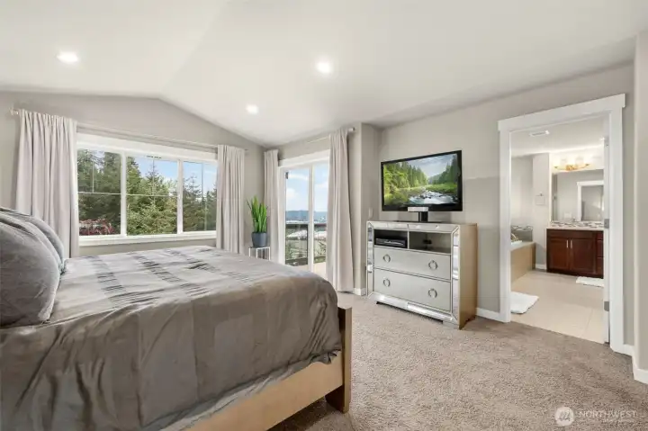 A second angle of the primary suite reveals the full picture — dual windows capturing valley views, private slider access to the upper deck, and a seamless entry into the en-suite bath beyond