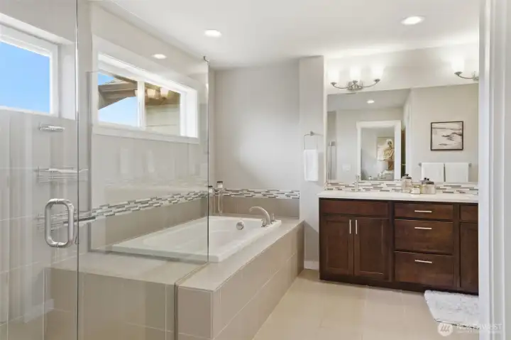 The primary en-suite impresses with a tile-surround soaking tub, glass-enclosed shower, dual vanity with quartz countertops, mosaic tile backsplash, and a private window bringing in natural light — a spa-caliber finish rarely found at this price point.