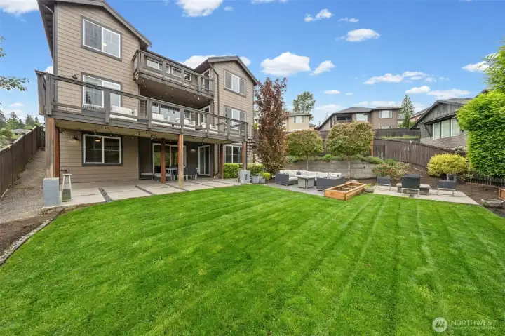 Entertain in style or simply unwind in this beautifully appointed backyard. A covered lower patio with string lighting flows seamlessly to open lawn space, with an upper deck above — offering multiple outdoor living zones perfect for year-round Pacific Northwest living.