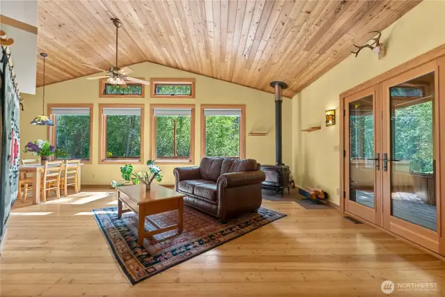 Wall of windows frames serene forest, meadow, and mountain views.