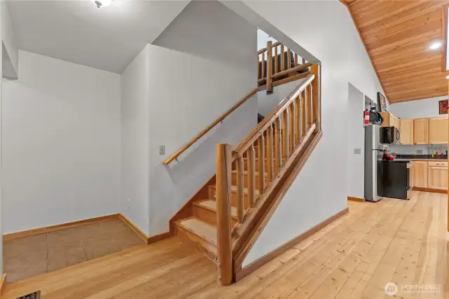 Warm wood staircase with log accents connects the open-concept main floor to the upstairs retreat, blending craftsmanship and comfort.