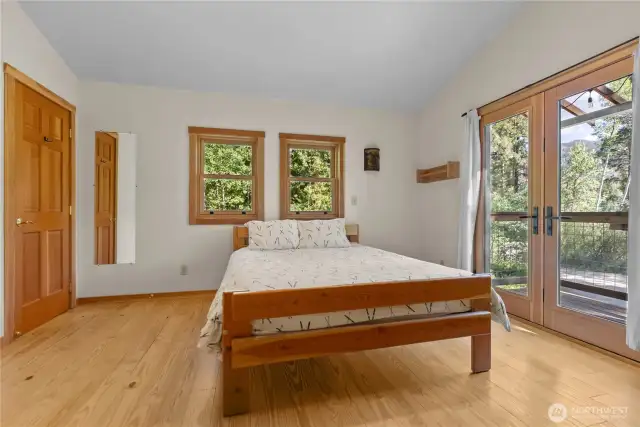 Spacious primary suite with vaulted ceiling, warm wood floors, and private balcony access—perfect for enjoying quiet morning views.