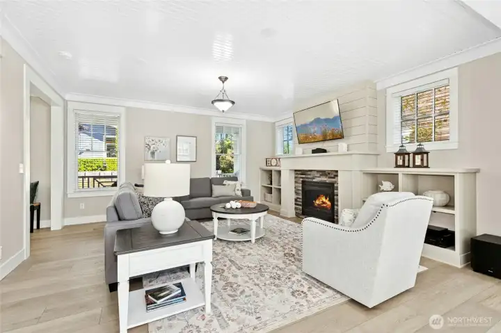 A bright, comfortable living room filled with natural light features a cozy fireplace and built-in shelves.