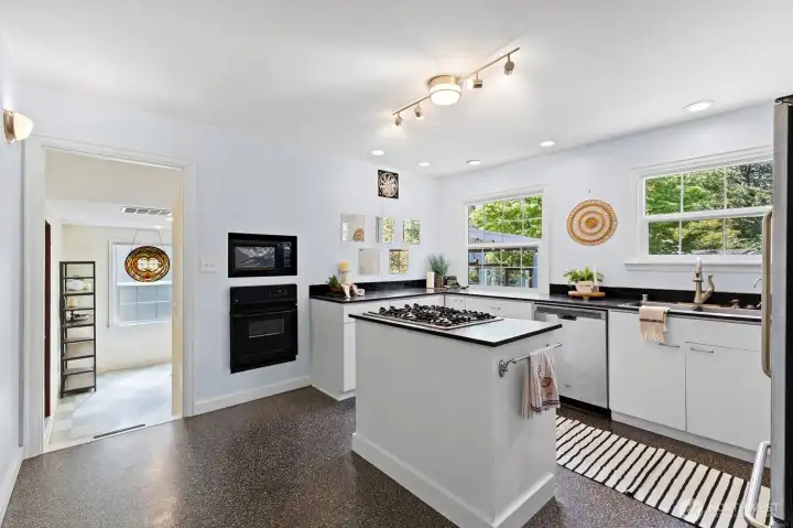 Centrally located kitchen with gas cooktop island, abundant natural light, and generous prep space.