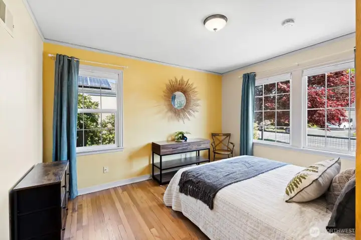 Main-level bedroom with hardwood floors, oversized windows, and cheerful natural light.