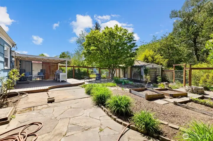 Expansive backyard retreat featuring raised garden beds, mature landscaping, and multiple outdoor gathering spaces.