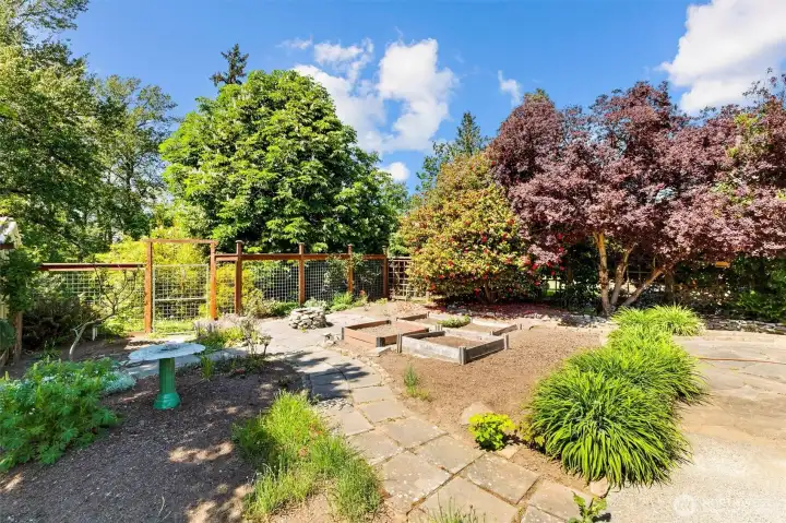 Backyard oasis with winding stone pathways, established gardens, and serene greenbelt ambiance.