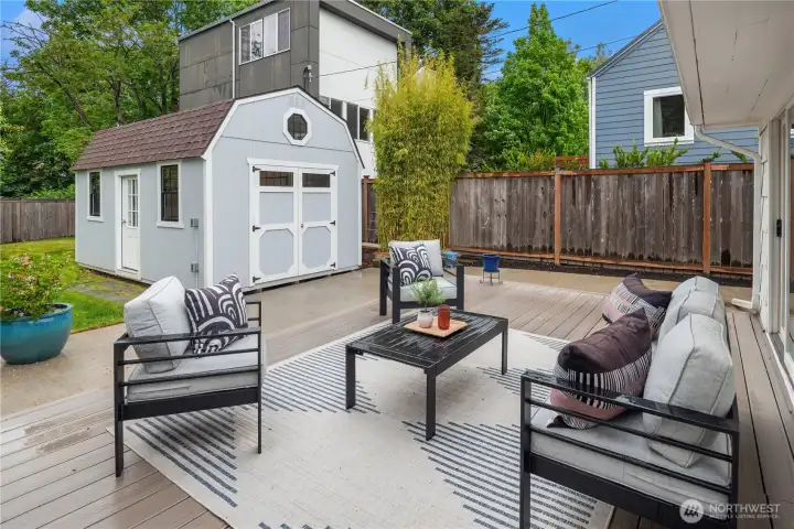 The spacious entertainment deck spans the entire backside of the house and ties into the concrete patio. Gated access to the driveway is off to the right.