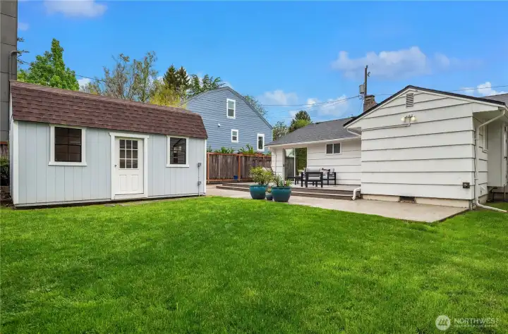 A fully fenced backyard with ample grass areas in addition to fantastic deck and patio areas. A wide gate to the front driveway is to the left of the house.