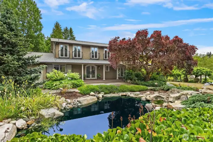 Front entrance showcasing the main house, featuring a view across the serene pond and waterfall.