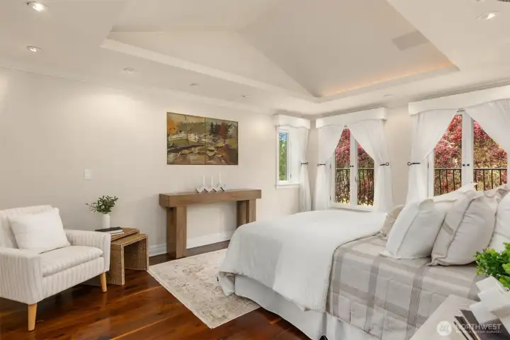 Primary suite featuring vaulted ceilings and an abundance of natural light through expansive windows.