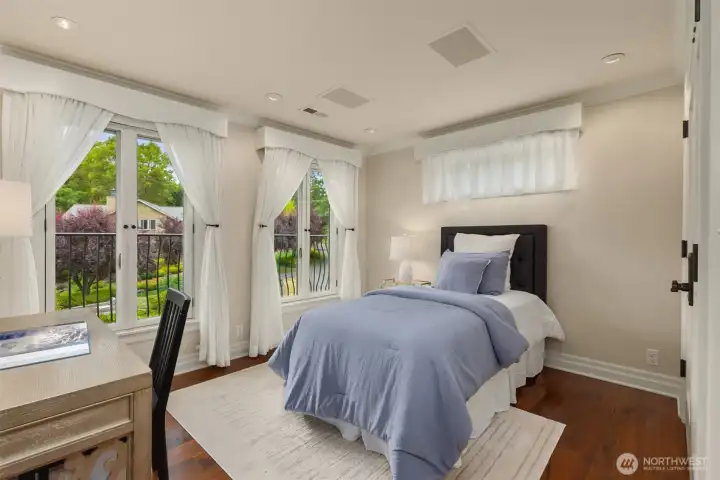 This guest bedroom offers a bright and airy atmosphere, highlighted by an abundance of natural light streaming through the plentiful, oversized windows. The room also features charming Juliet balconies that provide a perfect touch of elegance and fresh air, while the spacious walk-in closet offers extensive storage space to ensure a clutter-free and comfortable living environment.