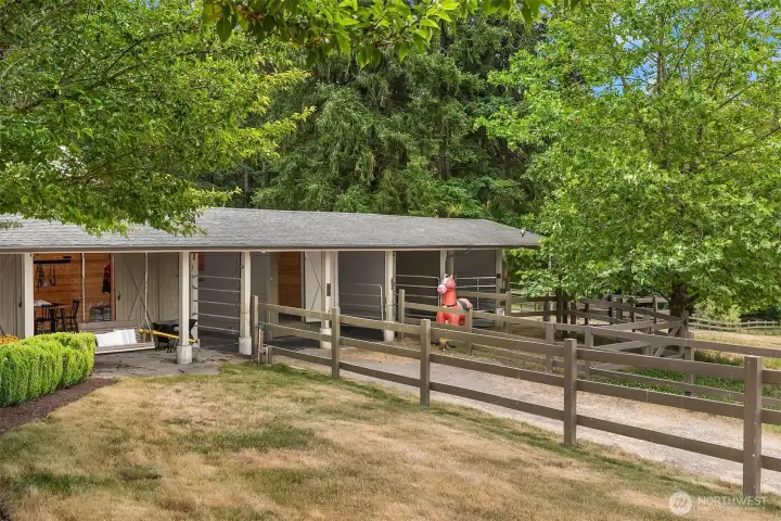 This barn features a spacious tack room, a feed room with a 1-ton hay capacity, and four paddocks, one of which converts to a dual paddock for foaling. It is conveniently located just steps away from the outdoor riding arena.