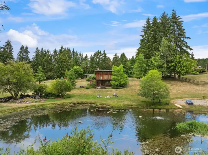 The rustic and cozy caretaker's cottage, known as "The Pond House," features two bedrooms and two bathrooms. It shares a drainfield and a drilled well with the studio building located behind it. Additionally, the property includes an aerated pond designed to maintain water circulation and deter mosquitoes.